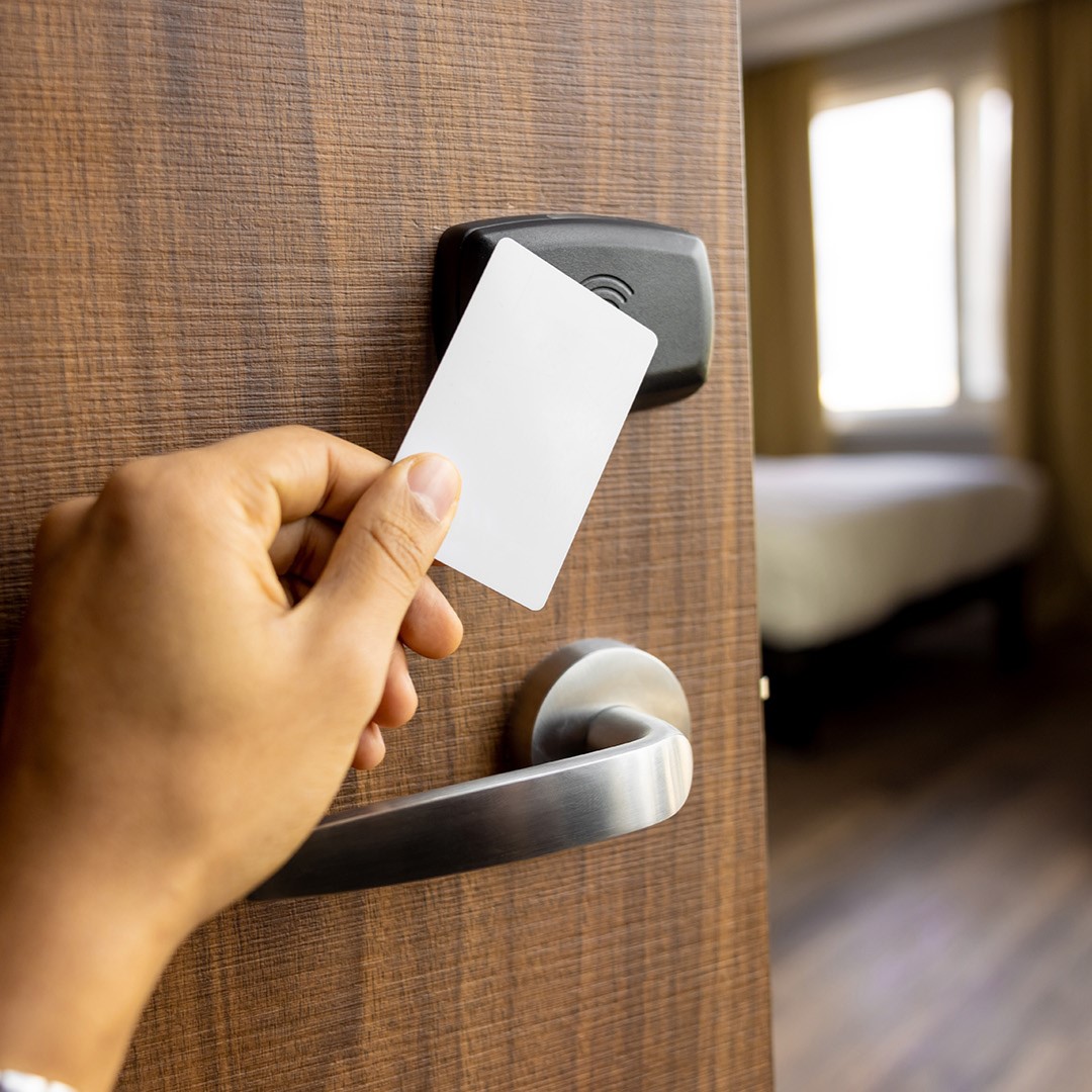 Persona che avvicina la card al lettore sulla porta della camera